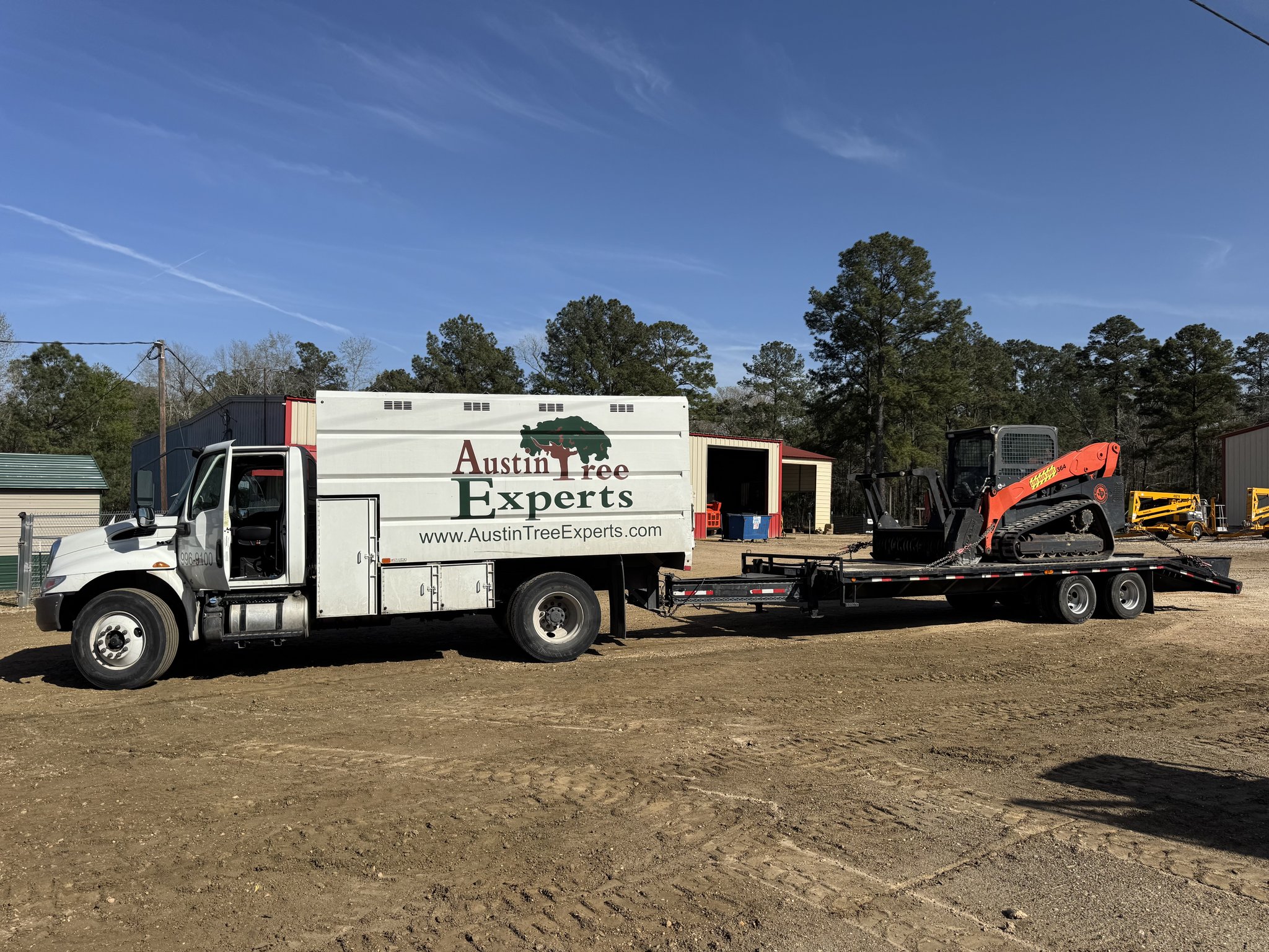 Austin Tree Experts truck with tracked mulching skid steer for fuel break work